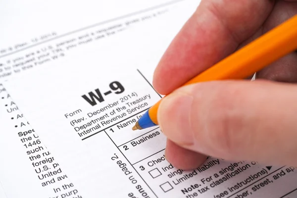 Hand with pen filling in form W-9 — Stock Photo, Image