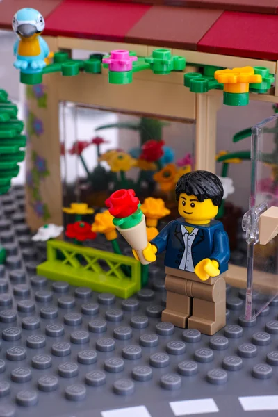 LEGO-Mann Minifigur mit Blumenstrauß kommt aus Blumenladen — Stockfoto