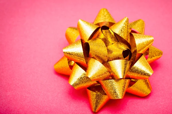 Golden bow on pink paper background — Stock Photo, Image