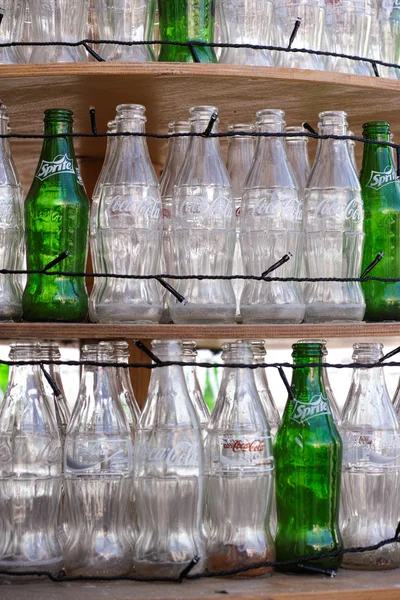 Empty bottles of Coca-Cola and Sprite on shelves — Stock Photo, Image