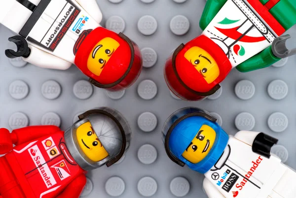 Cuatro minifiguras del conductor de Lego en la placa base gris — Foto de Stock
