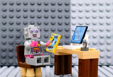 Lego robot minifigure ile bilgisayar başında oturan öğretim