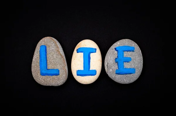 Word Lie spell out from stones with blue letters