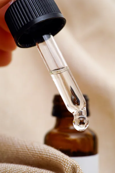 Pipette with essential oil with  bottle in background — Stock Photo, Image