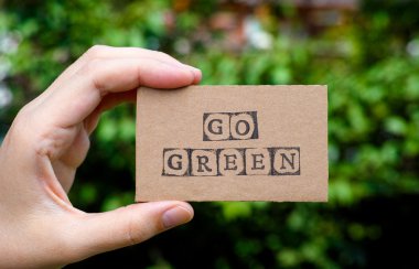 Go Green kelimelerle karton kartı tutan kadın el 