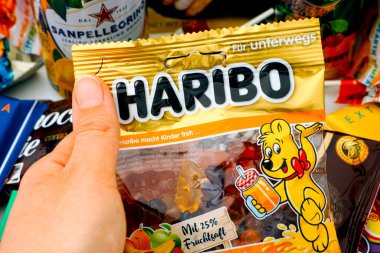 Tambov, Rusya Federasyonu - 30 Ekim 2020 Haribo Bears şekerlerinden bir paket alan kadın. Arka planda bir sürü tatlı atıştırmalık ve içecek var.. 