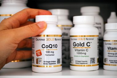Tambov, Rusya Federasyonu - 28 Ekim 2020 Bir şişe CoQ10 'u dolaptan California Gold Nutrition' dan çıkaran kişi