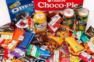 Tambov, Rusya Federasyonu - 30 Ekim 2020 tatlı abur cubur yığını ve masada içki kavanozları. Oreo, Choco-Pie, Ritter Sport, Haribo, Chupa Fincan, YumEarth, Sanpellegrino, Perrier markaları var..
