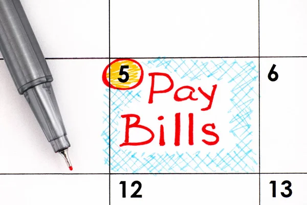 Reminder Pay Bills in calendar with pen. Close-up