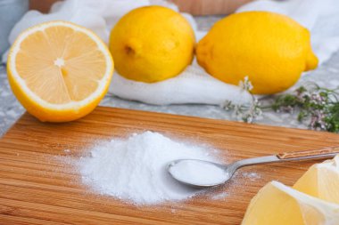 Mutfak tahtasına çay kaşığı karbonat yığını. Yakınlarda limonlar var..