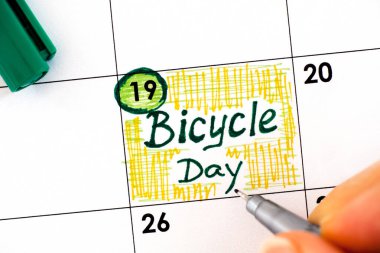 Takvimde kalem yazan kadın parmakları Bisiklet Günü 'nü hatırlatıyor. 19 Nisan. 
