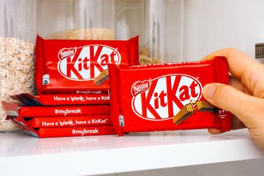 Tambov, Russian Federation - March 19, 2021 Woman hand taking KitKat chocolate bar by Nestle from shelf of kitchen cupboard clipart