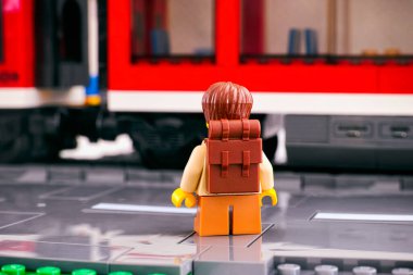 Tambov, Rusya Federasyonu - 03 Mart 2021 Sırt çantalı bir Lego turisti kırmızı trenin önündeki platformda sırtı kameraya dönük duruyor