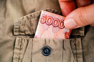 Bir kadın, bej bir ceketin cebinden beş bin ruble alıyor. Yakın plan.