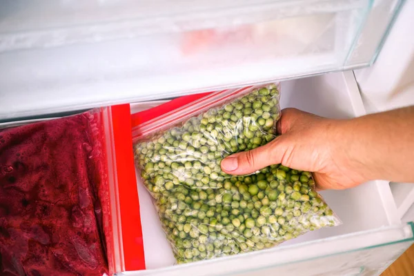 Vrouw Hand Neemt Zelfgemaakte Verpakking Van Groene Erwten Uit Vriezer — Stockfoto