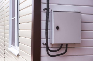 Evin dışındaki duvarda elektrik kabloları olan bir panel. Yakın plan.