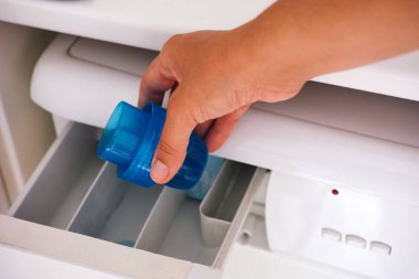 Kadın eli çamaşır makinesine sıvı deterjan döküyor.. 