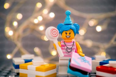 Tambov, Rusya Federasyonu - 17 Ocak 2021 Lego doğum günü kızı lolipoplu minyatür figür ve gri tabağa karşı Noel arkaplanlı hediyeler