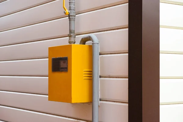 Yellow Gas Meter Box with gas pipes in it on a wall outside the house. Close-up