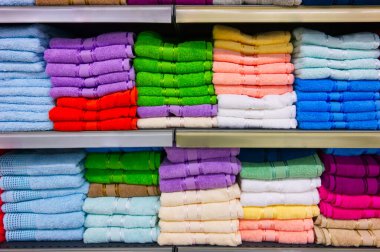Raflarda bir sürü renkli havlu yığını var.
