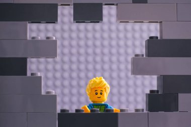 Tambov, Rusya Federasyonu - 26 Ağustos 2020 Lego Çocuk gri bir duvardaki delikten bakıyor.