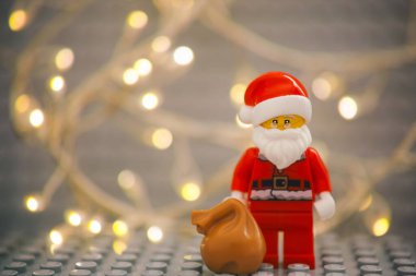 Tambov, Rusya Federasyonu - 17 Ocak 2021 Lego Noel Baba minyatür figürü Noel ışıkları arka planında bir çanta dolusu hediyeyle. Sığ alan derinliği