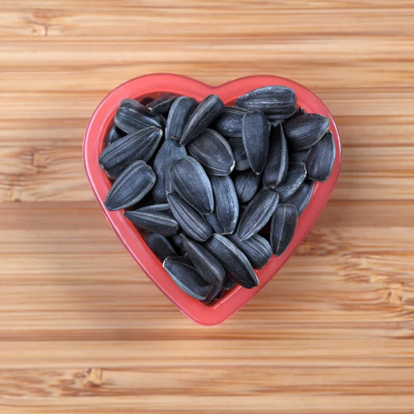 Sunflower seed in a heart bowl — Stock Photo, Image