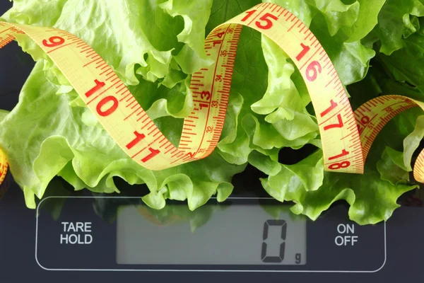 Green lettuce and tape measure on kitchen scale — Stock Photo, Image