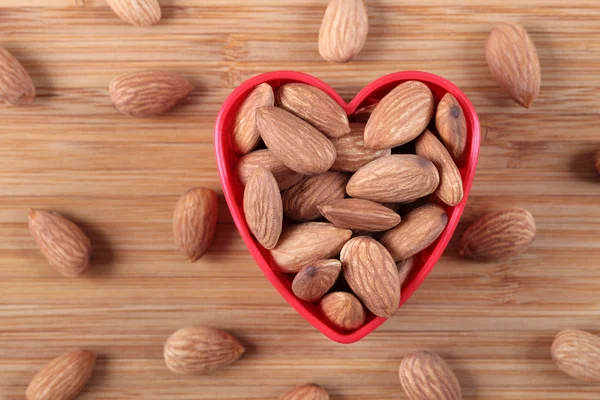 Almonds in a heart bowl — Stock Photo, Image