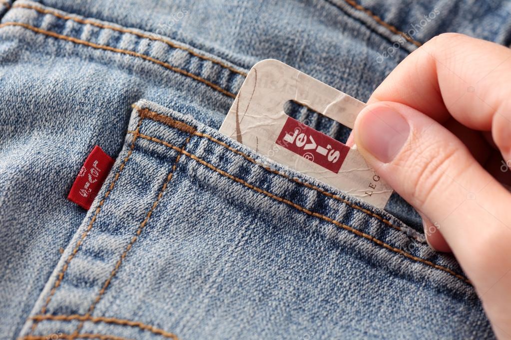 Tambov, Russian Federation - October 21, 2012 Woman's hand taking out label logo  from pocket of a pair Levi's Jeans. Studio shot. Levi Strauss & Co. is a American clothing company was founded in 1853. It known worldwide for its Levi's brand of denim