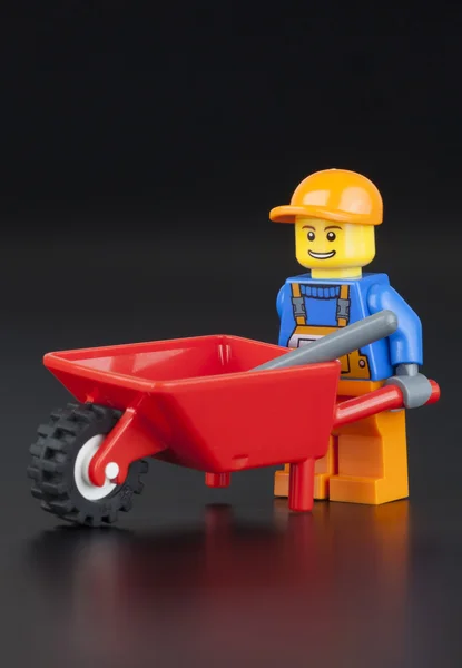 Minifigura de trabajador de LEGO con carretilla roja vacía — Foto de Stock