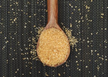 Kahverengi şeker kamışı bir tahta kaşık içinde