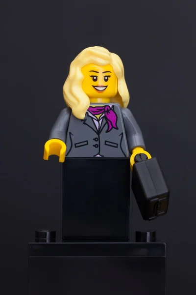 Лего бизнесвумен минифигурка с черным чемоданом — стоковое фото