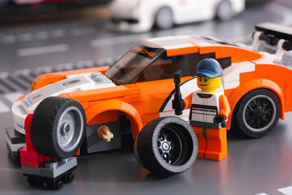 Lego driver is fixing wheel of Porsche 911 GT — Stock Photo, Image