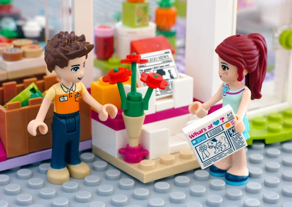 Lego menino e menina com jornal perto de rack de revista — Fotografia de Stock