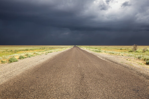 Старая дорога в пустыне и штормовое небо
