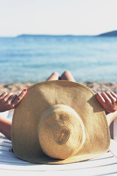 Tropikal, şapka ile plajda güneşlenirken kadın