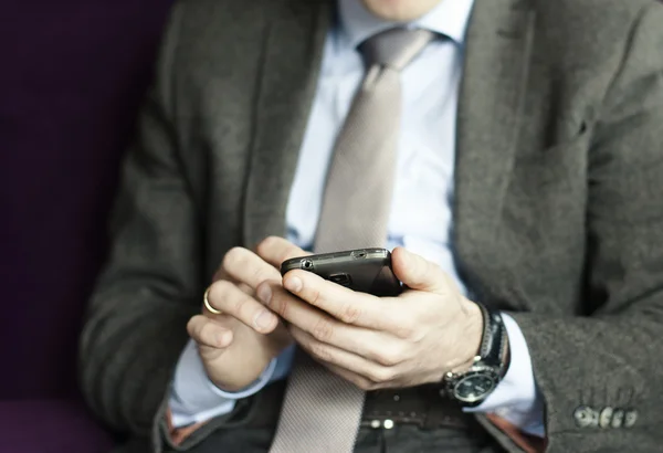 Podnikatel v oblek, sako, košili, kravatu, pomocí jeho chytrý telefon — Stock fotografie
