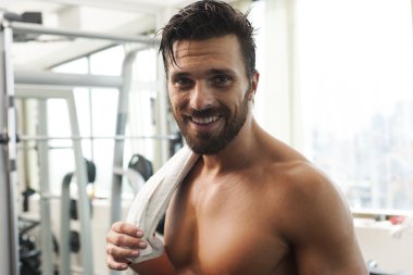 Young strong fit man smiling, exercising in the gym