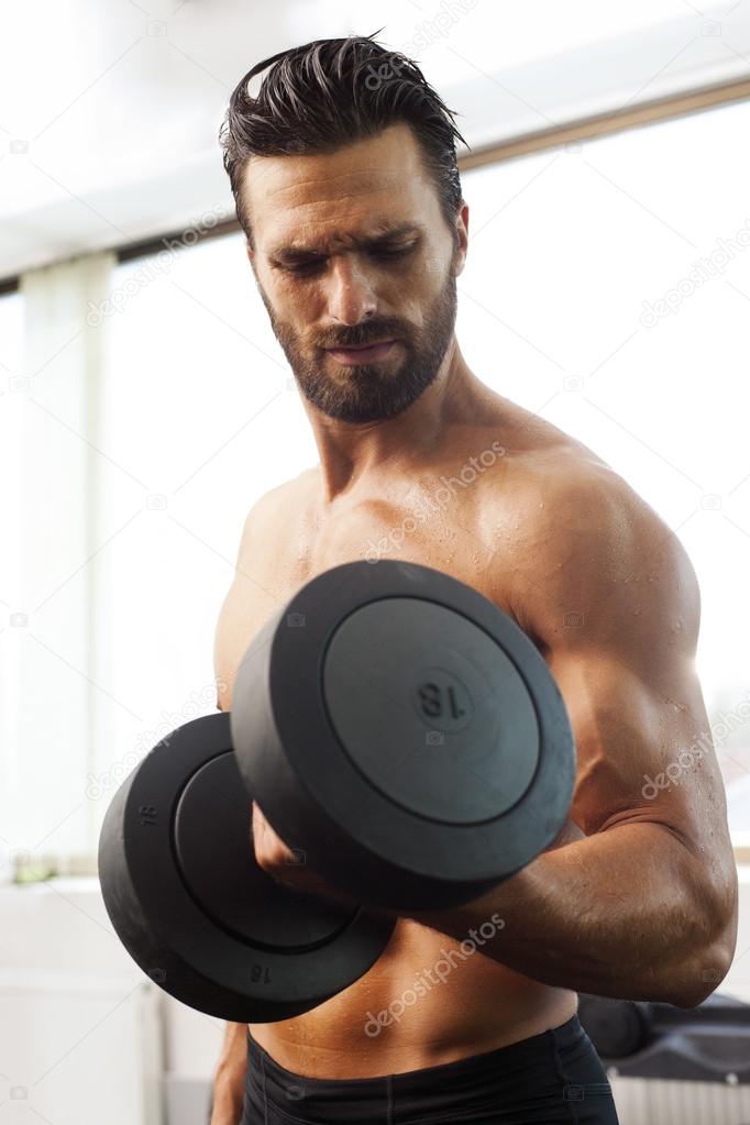 Young strong fit man smiling, exercising in the gym
