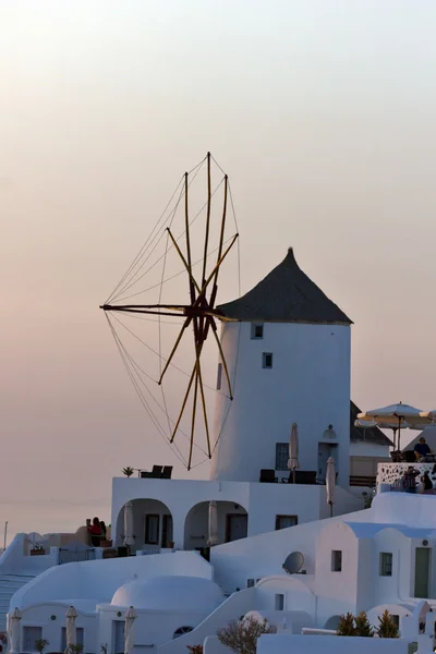 Matahari terbenam di atas kincir angin putih di kota Oia dan panorama ke pulau Santorini — Stok Foto