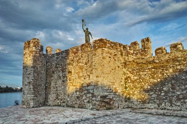 Sunset at port of Nafpaktos town and monument over Castle wall clipart