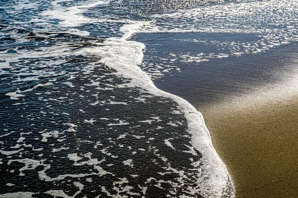 Přílivová vlna na písečné pobřeží — Stock fotografie