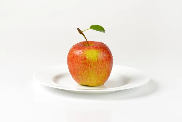 Мытое красное яблоко на тарелке — стоковое фото