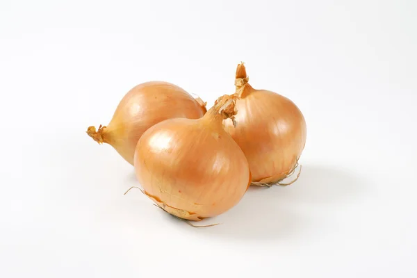 Three raw onions on white background — Stock Photo, Image