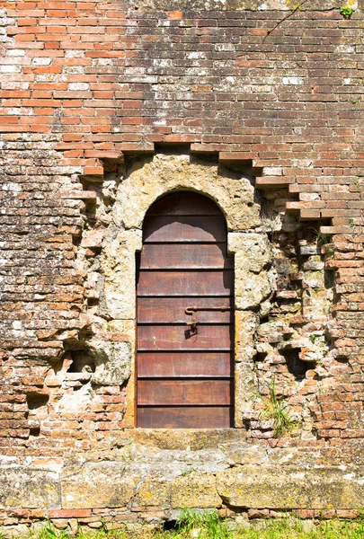 Old wooden door in aged brick wall — Stock Photo, Image