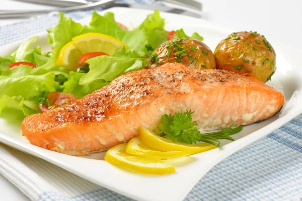 Salmon fillet with roasted potatoes and fresh vegetables Royalty Free Stock Photos