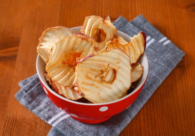 Bir kase kuru elma dilimi - elma cipsi ya da yüzük - gri peçeteye.