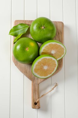 Kesme tahtasında bal meyveleri (yeşil greyfurtlar, pomelitler)