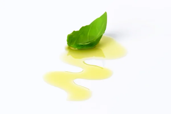 Olive oil drizzle and basil leaf — Stock Photo, Image